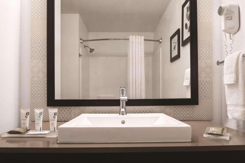 La salle de bains est pourvue d'un lavabo blanc et d'un miroir. dans l'établissement Country Inn & Suites by Radisson, Cottage Grove, MN, à Cottage Grove
