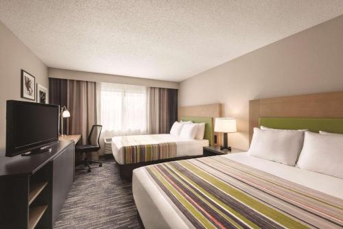 a hotel room with two beds and a flat screen tv at Country Inn & Suites by Radisson, Northfield, MN in Northfield