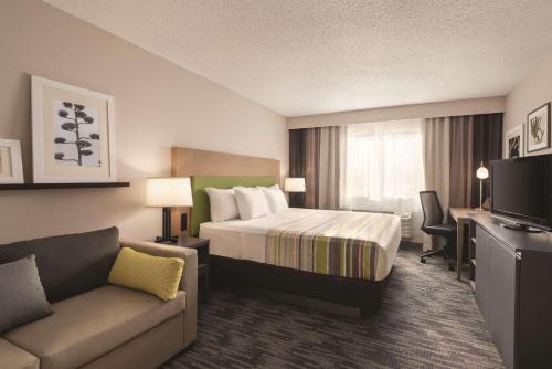 ノースフィールドにあるCountry Inn & Suites by Radisson, Northfield, MNのベッドとソファ付きのホテルルーム