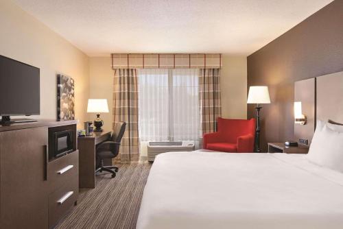 a hotel room with a bed and a red chair at Country Inn & Suites by Radisson, Albert Lea - Austin in Albert Lea