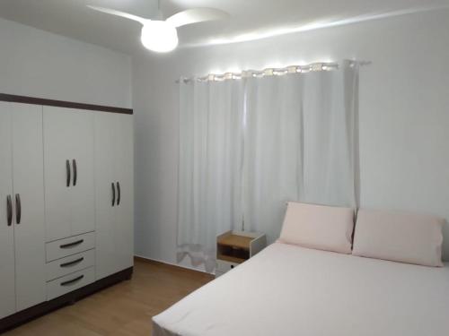 Apartamento 3/4, 1 suíte Vog Atlântico في ايليوس: غرفة نوم بسرير ابيض وخزانة بيضاء