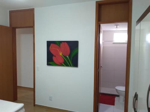 a bathroom with a toilet and a painting on the wall at Apartamento 3/4, 1 suíte Vog Atlântico in Ilhéus