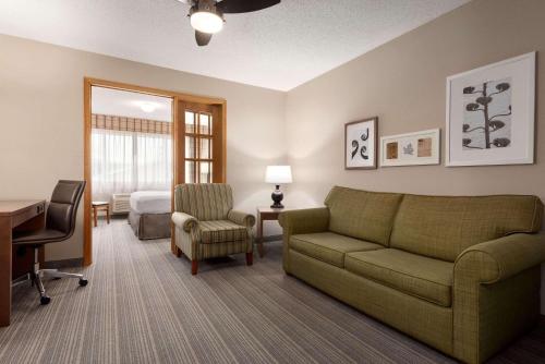 a living room with a couch and a desk and a bed at Country Inn & Suites by Radisson, Baxter, MN in Baxter
