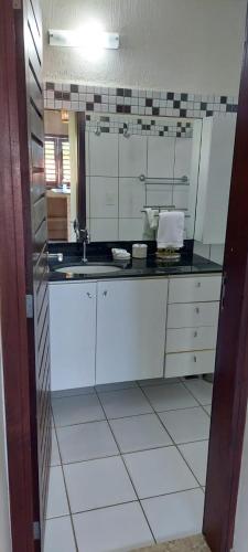 a kitchen with white cabinets and a large mirror at Apartamento PIPA - UF01 in Pipa