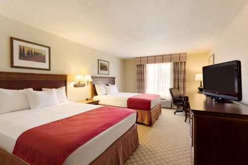 a hotel room with two beds and a flat screen tv at Country Inn & Suites by Radisson, Nevada, MO in Nevada