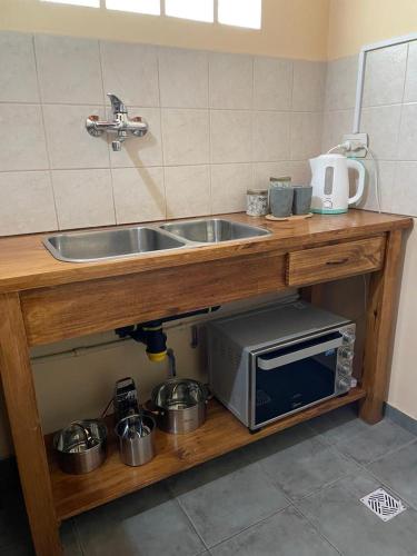 a kitchen with a sink and a microwave under a counter at Alojamiento ¨El Puente¨ en El Bolsón, para dos personas. in El Bolsón