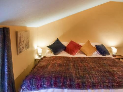 a bedroom with a large bed with colorful pillows at Cherry Cottage in Ipswich