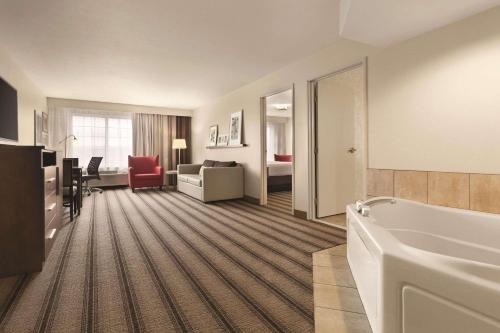 a hotel room with a tub and a bedroom at Country Inn & Suites by Radisson, Billings, MT in Billings