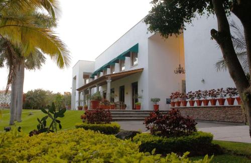un edificio blanco con palmeras y arbustos en Radisson Hotel Cuernavaca en Cuernavaca