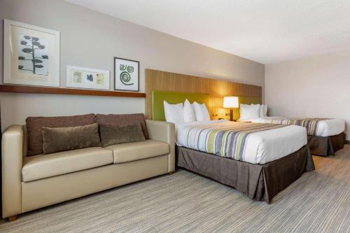 ランバートンにあるCountry Inn & Suites by Radisson, Lumberton, NCのベッドとソファ付きのホテルルーム