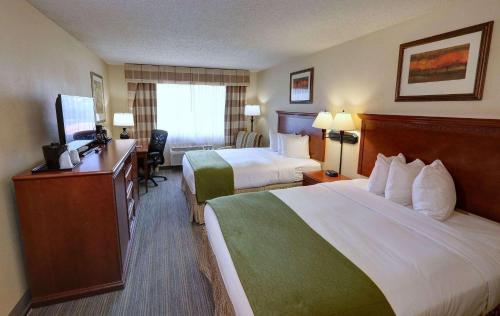 a hotel room with two beds and a desk at Country Inn & Suites by Radisson, Charlotte I-85 Airport, NC in Charlotte