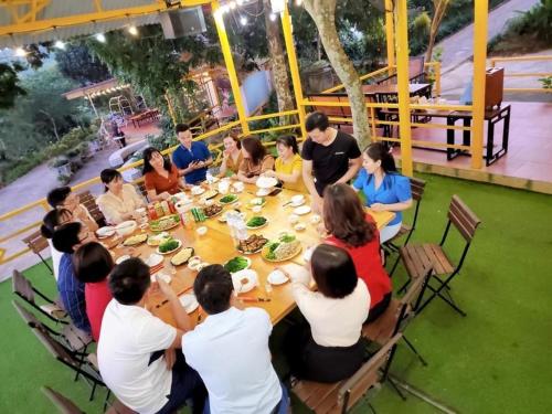 een groep mensen die rond een tafel zitten te eten bij SenHomestay 