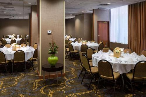 un comedor con mesas y sillas blancas y un jarrón en Radisson Hotel Bismarck en Bismarck