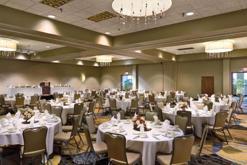 un salón de banquetes con mesas y sillas blancas y lámparas de araña en Radisson Hotel Bismarck en Bismarck