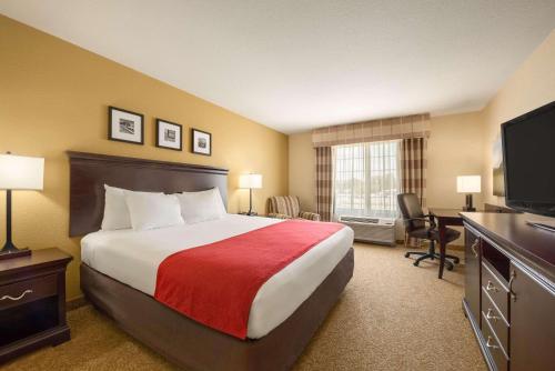 a hotel room with a bed and a flat screen tv at Country Inn & Suites by Radisson, Minot, ND in Minot