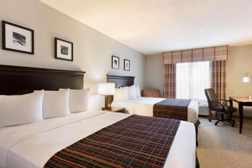 a hotel room with two beds and a desk at Country Inn & Suites by Radisson, Kearney, NE in Kearney