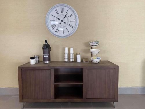 a clock on the wall above a wooden cabinet at Country Inn & Suites by Radisson, Lincoln Airport, NE in Lincoln