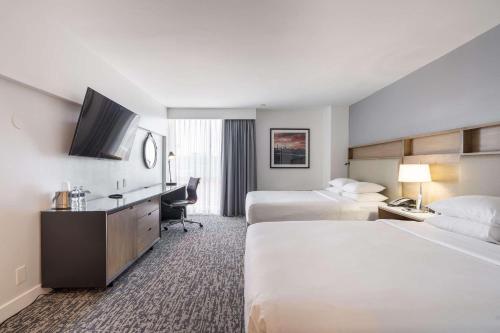 ein Hotelzimmer mit 2 Betten und einem Schreibtisch in der Unterkunft Radisson Hotel JFK Airport in Queens