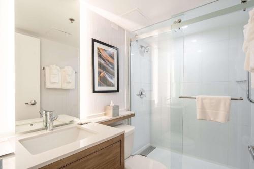 a white bathroom with a sink and a shower at Radisson Hotel JFK Airport in Queens
