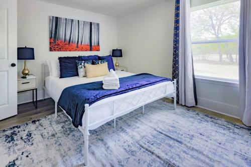 1 dormitorio con 1 cama con edredón azul y ventana en Manchaca Meadows - 4 Bedroom Villa, en Manchaca
