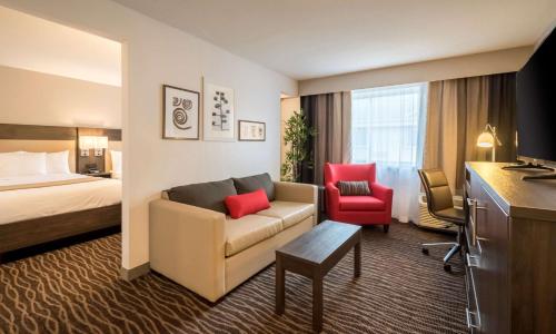 a hotel room with a couch and a bed at Country Inn & Suites by Radisson, Rochester-Pittsford-Brighton, NY in Rochester
