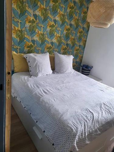 un lit avec des draps blancs et des oreillers dans une chambre dans l'établissement Tropicale chic, à La Mulatière