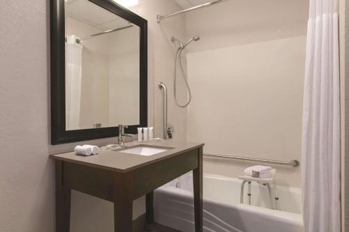 a bathroom with a sink and a tub with a mirror at Country Inn & Suites by Radisson, Port Clinton, OH in Port Clinton