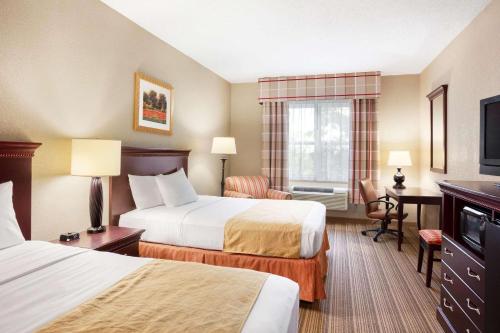 イサカにあるCountry Inn & Suites by Radisson, Ithaca, NYのベッド2台とデスクが備わるホテルルームです。