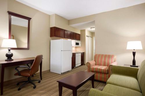 a living room with a couch and a desk and a refrigerator at Country Inn & Suites by Radisson, Ithaca, NY in Ithaca