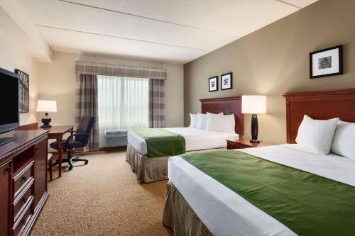 a hotel room with two beds and a desk at Country Inn & Suites Buffalo South I-90, NY in West Seneca