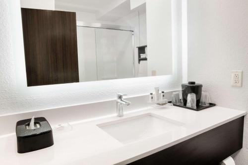 La salle de bains est pourvue d'un lavabo blanc et d'un miroir. dans l'établissement Country Inn & Suites by Radisson, Columbus West, OH, à Columbus