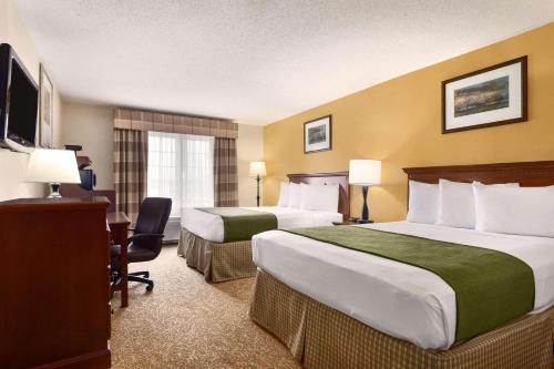 a hotel room with two beds and a desk at Country Inn & Suites by Radisson, Marion, OH in Marion
