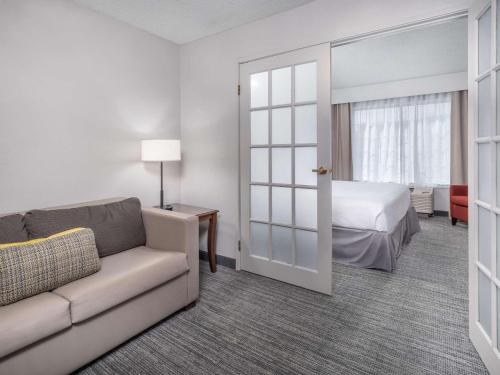 Country Inn & Suites by Radisson, Toledo, OH في ماومي: غرفة معيشة مع أريكة وسرير