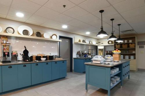 a large kitchen with blue cabinets and plates on the shelves at Country Inn & Suites by Radisson, Oklahoma City Airport, OK in Oklahoma City