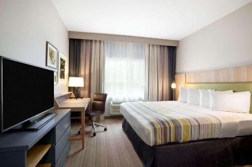 Habitación de hotel con cama, escritorio y TV. en Country Inn & Suites by Radisson, Enid, OK, en Enid