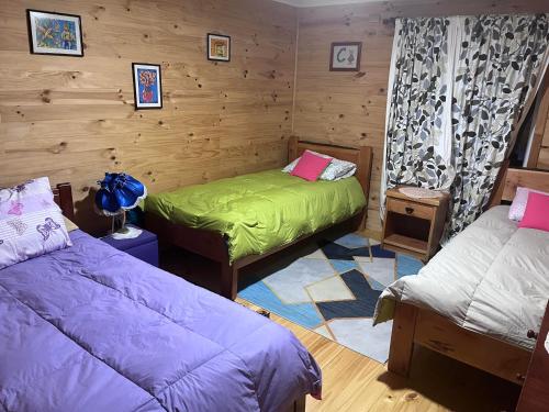 2 camas en una habitación con paredes de madera en Casa Huillinco, en Castro
