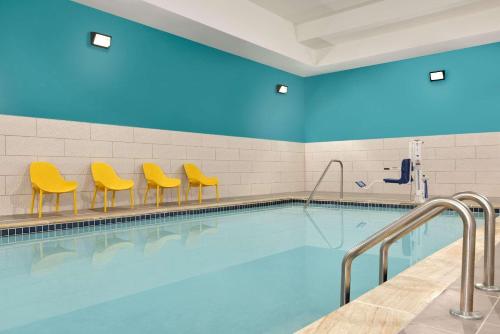 uma piscina com cadeiras amarelas e paredes azuis em Park Inn by Radisson, Florence, SC em Florence