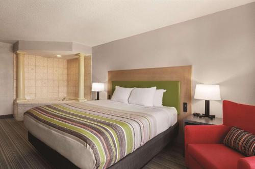 a hotel room with a bed and a red chair at Country Inn & Suites by Radisson, Beaufort West, SC in Beaufort