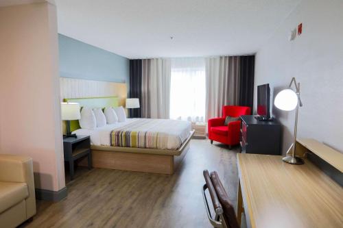 a hotel room with a bed and a red chair at Country Inn & Suites by Radisson, Myrtle Beach, SC in Myrtle Beach