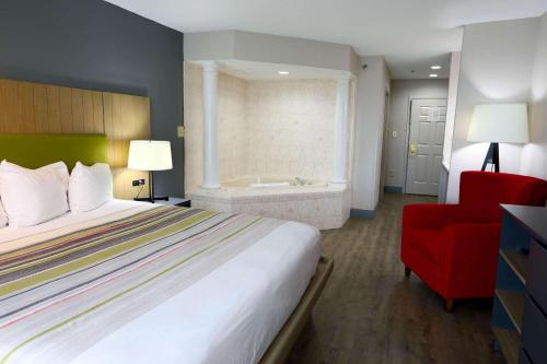 a hotel room with a bed and a red chair at Country Inn & Suites by Radisson, Myrtle Beach, SC in Myrtle Beach