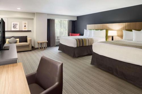 a hotel room with two beds and a couch at Country Inn & Suites by Radisson Downtown, Gatlinburg, TN in Gatlinburg