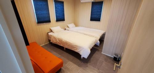 two beds in a small room with two windows at きくのこ3缶ヴィラ＆テラス　 in Miyako Island