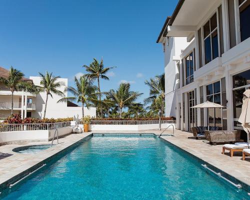 a swimming pool in front of a building with palm trees at Four Seasons Resort Oahu at Ko Olina in Kapolei