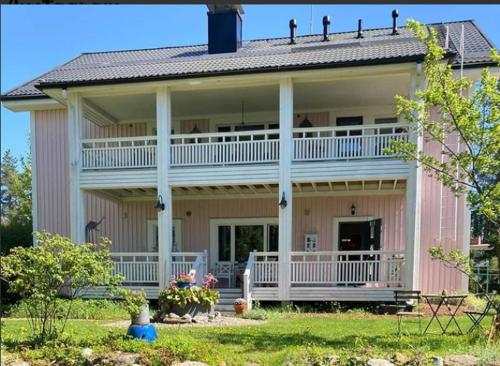 a large pink house with a large porch at Wanha Neuvola Guesthouse in Pieksamaki