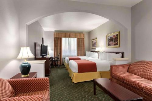 a hotel room with two beds and two chairs at Country Inn & Suites by Radisson, Fort Worth West l-30 NAS JRB in Fort Worth