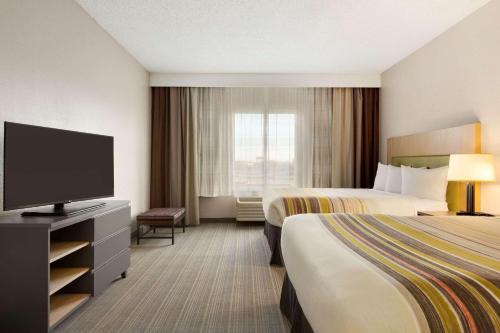 ラウンドロックにあるCountry Inn & Suites by Radisson, Austin North Pflugerville , TXのベッド2台、薄型テレビが備わるホテルルームです。