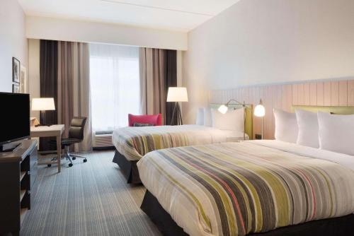 a hotel room with two beds and a desk at Country Inn & Suites by Radisson, Katy Houston West , TX in Katy