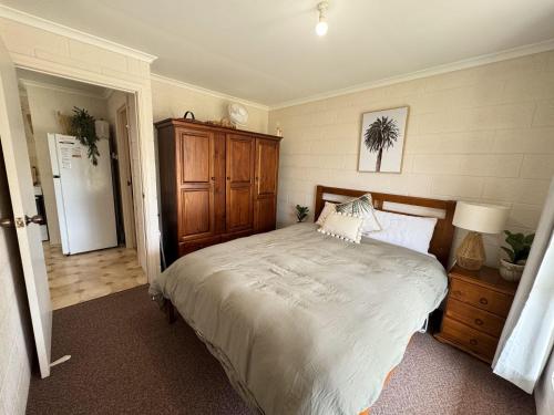 a bedroom with a large bed and a wooden cabinet at The J's - Pets welcome outside in Robe