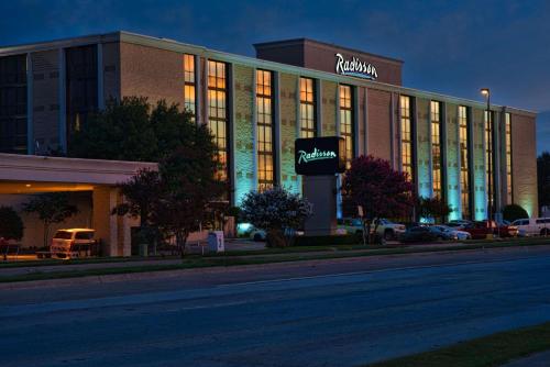 a building with a sign on the side of a street at Radisson Hotel Fort Worth North-Fossil Creek in Fort Worth