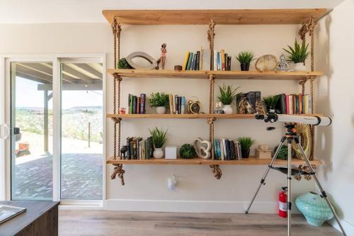 una habitación con estanterías llenas de libros y plantas en The Invisible Wind Cabin- Joshua Tree Amazing View, en Yucca Valley